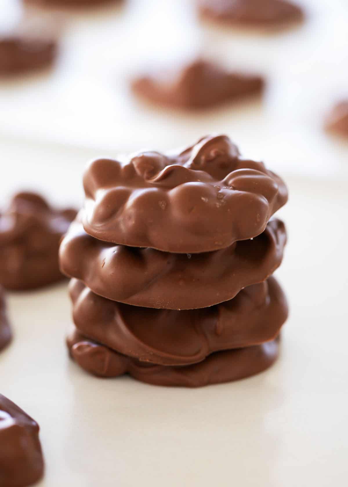 Only 5 ingredients are needed for this crockpot candy. Two kinds of chocolate, almond bark, peanut butter chips and peanuts are a slow cooker treat that is a holiday favorite! Stack of crockpot candy.
