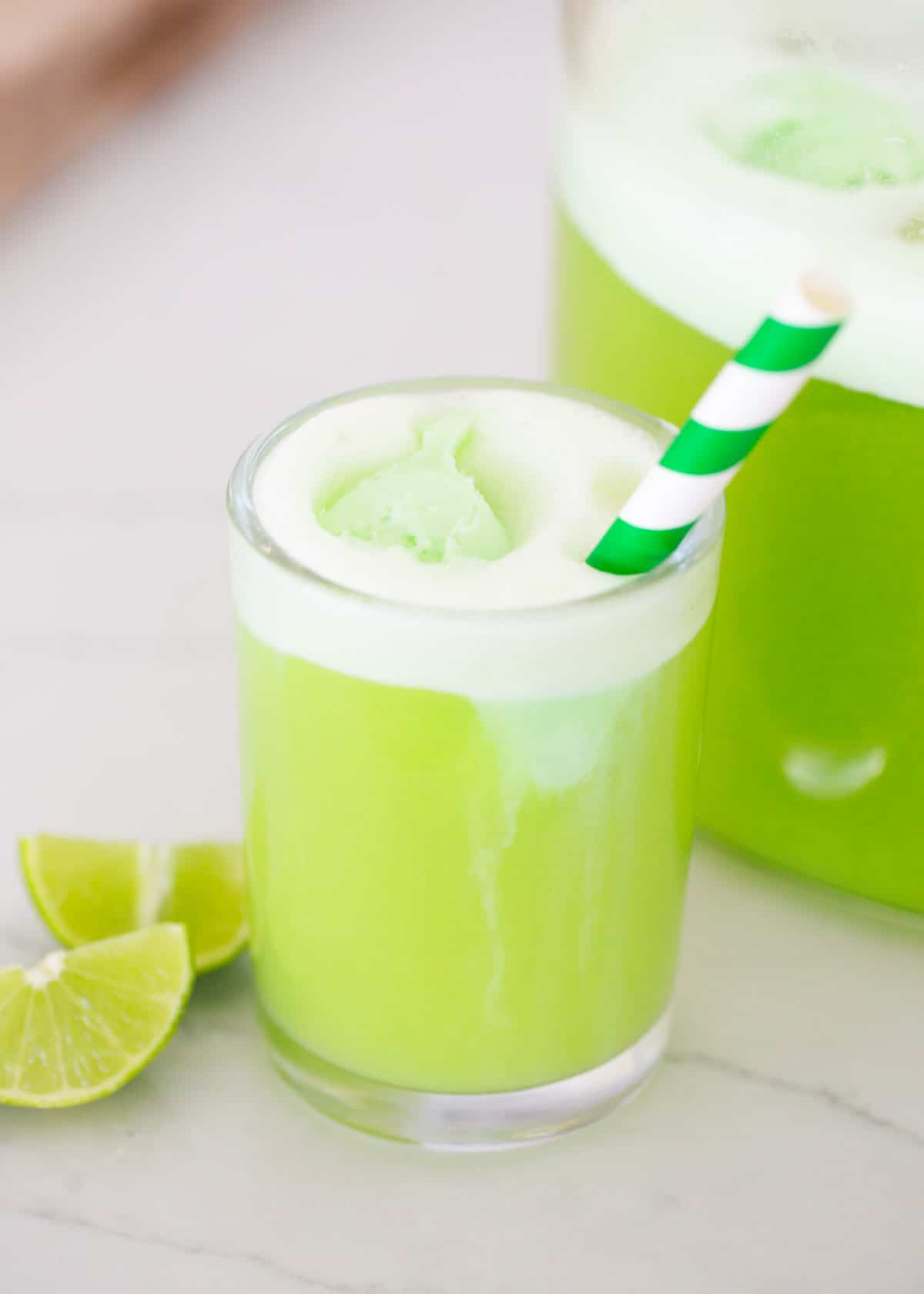 This green punch is a kid-friendly drink recipe made with lemon-lime soda and green sherbet. Simple ingredients make it easy to whip up in 5 minutes for any party! Green punch in a glass cup.