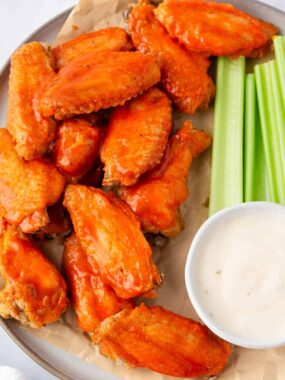 Crispy baked buffalo chicken wings dipped in creamy ranch dressing with celery sticks on the side.