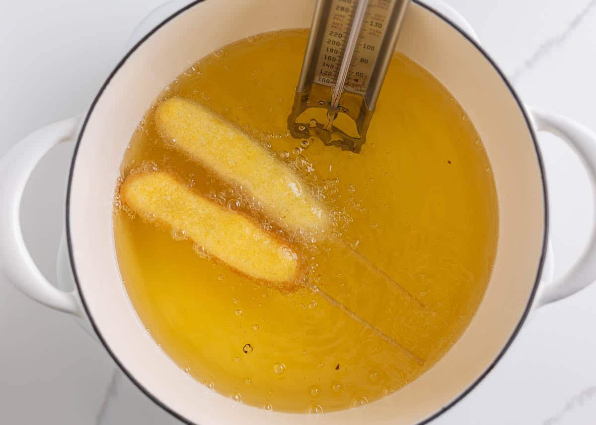 Homemade corn dogs frying in hot oil until golden brown