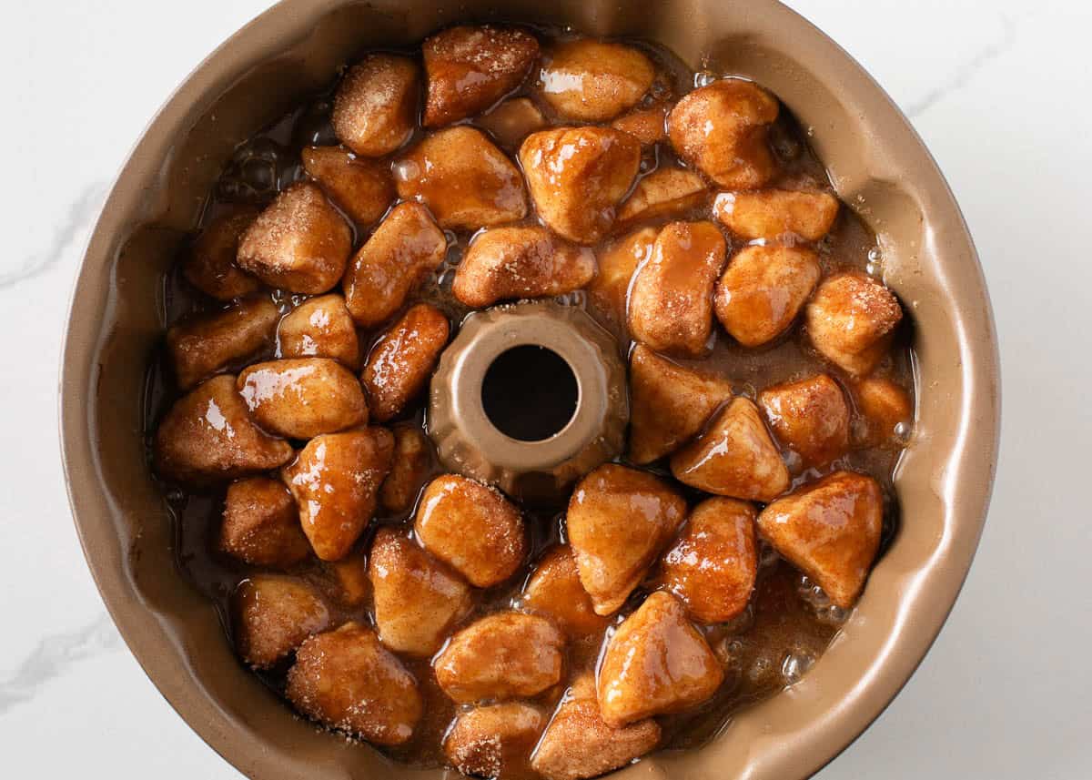 Biscuit pieces in a bundt pan with brown sugar and butter.