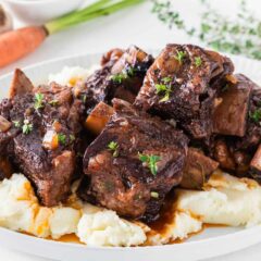 Red wine braised short ribs served over creamy mashed potatoes with a rich sauce and fresh thyme.