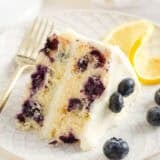 A slice of lemon blueberry cake on a white plate.