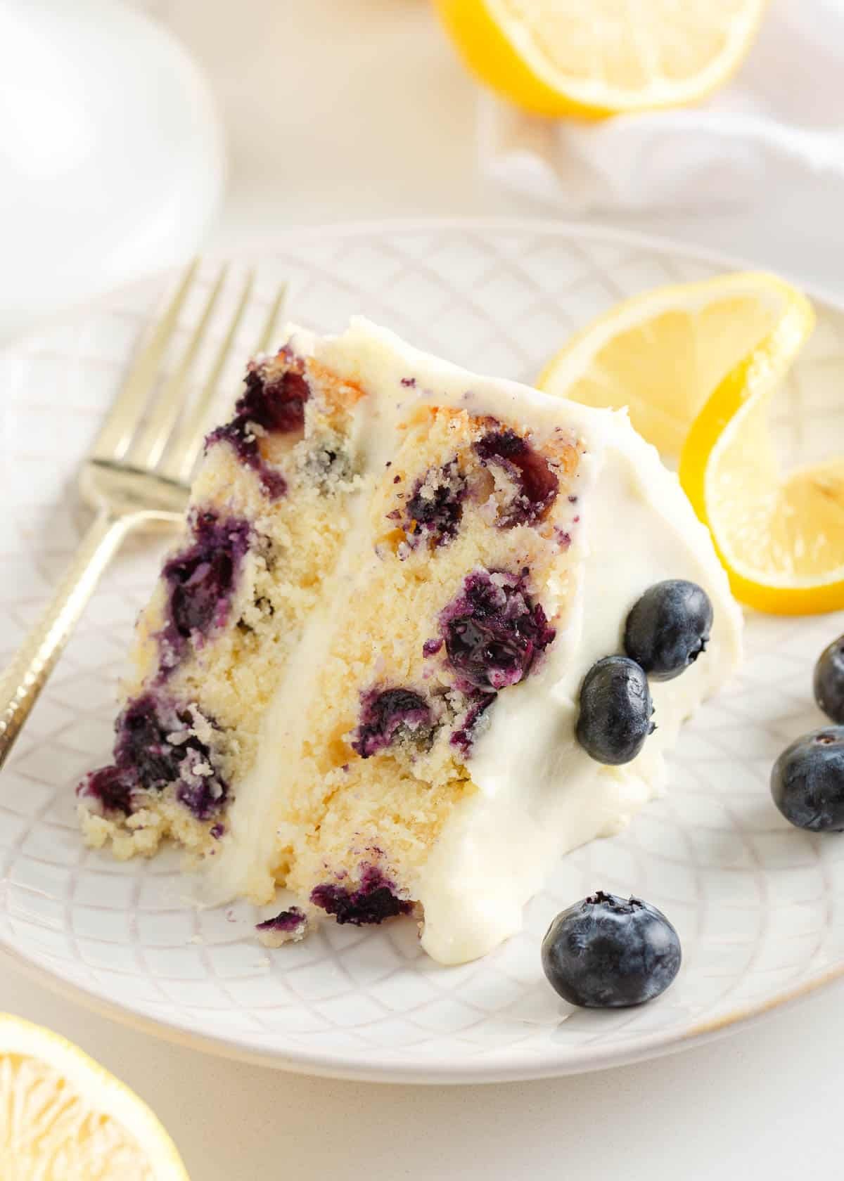 A slice of lemon blueberry cake on a white plate.