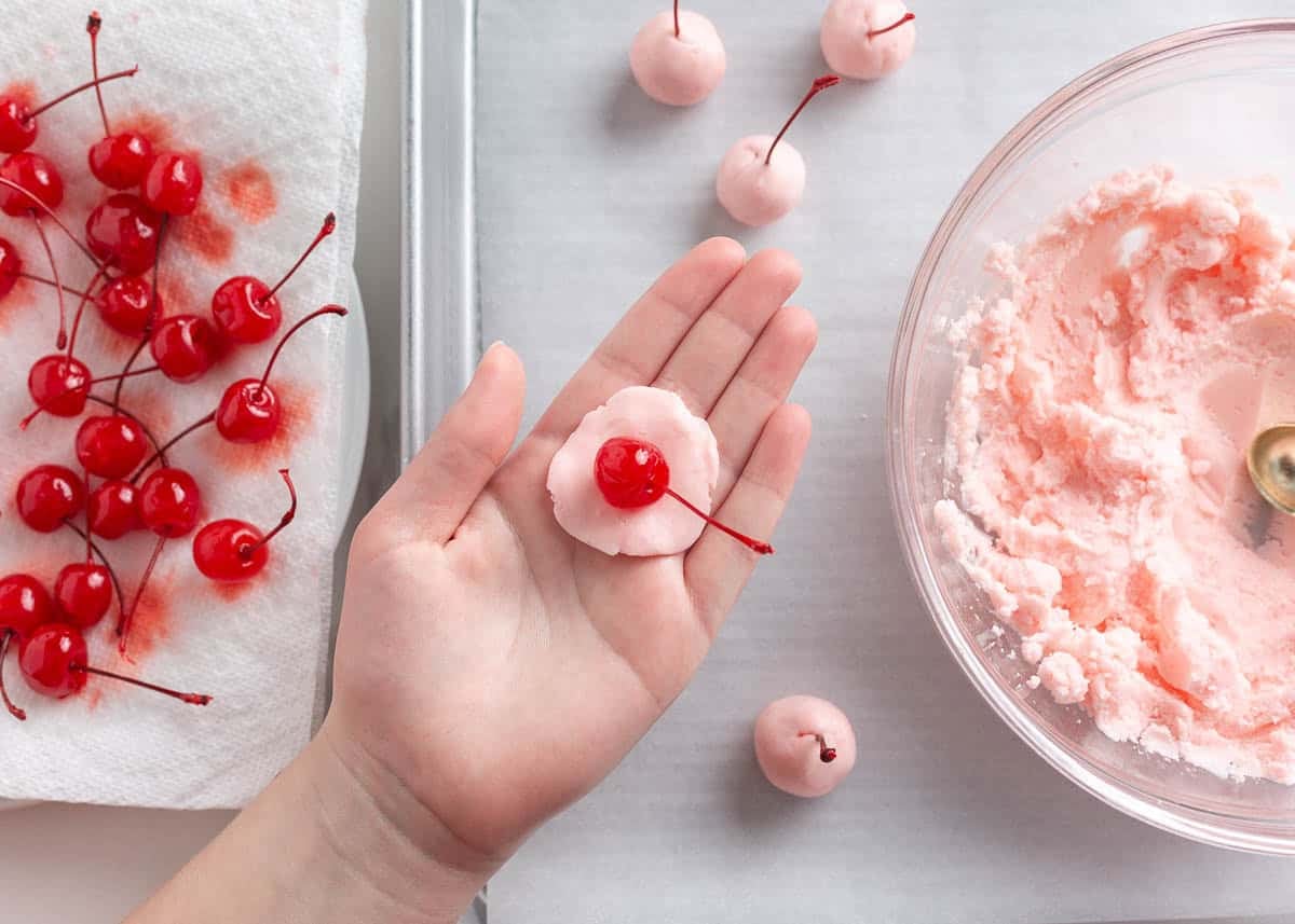 Wrapping a maraschino cherry in the sugar mixture to form the liquid center for homemade chocolate covered cherries.