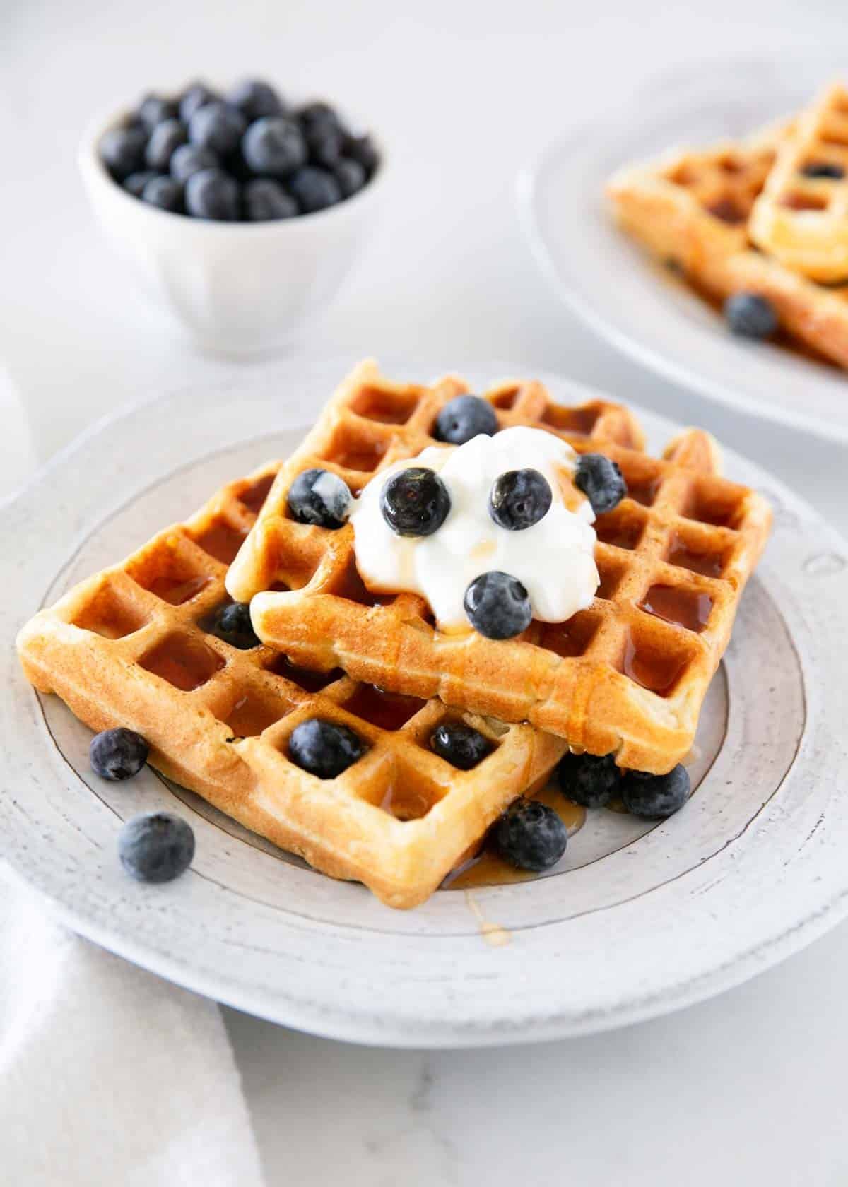 Put sourdough starter or discard to use and make a batch of fluffy sourdough waffles with buttermilk and pantry staples. Enjoy them right away or ferment batter overnight! Sourdough waffles on a plate with blueberries.