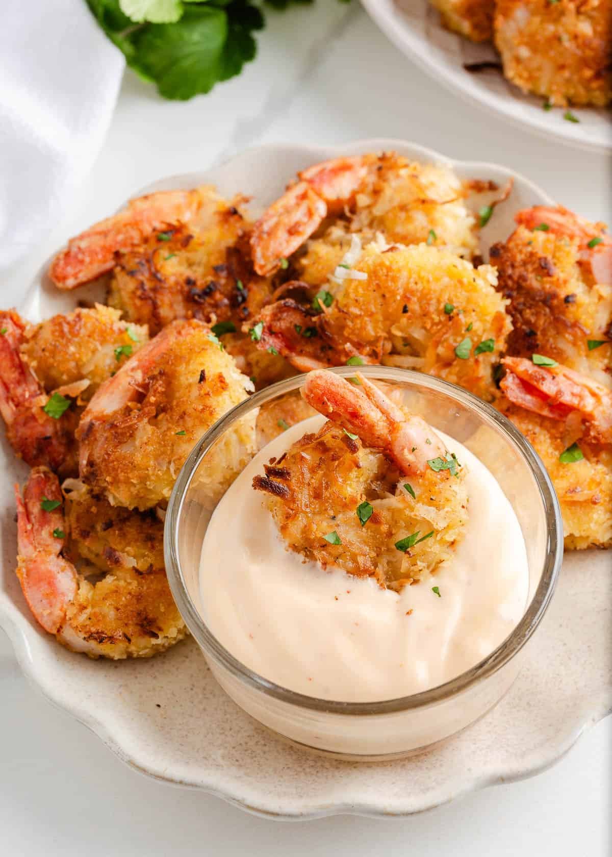 Coconut shrimp with dipping sauce on a plate.