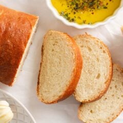 Homemade Italian bread sliced on the counter with dipping oil in a bowl.