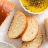 Sliced homemade Italian bread on counter with dipping oil.