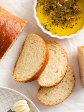 Sliced homemade Italian bread on counter with dipping oil.