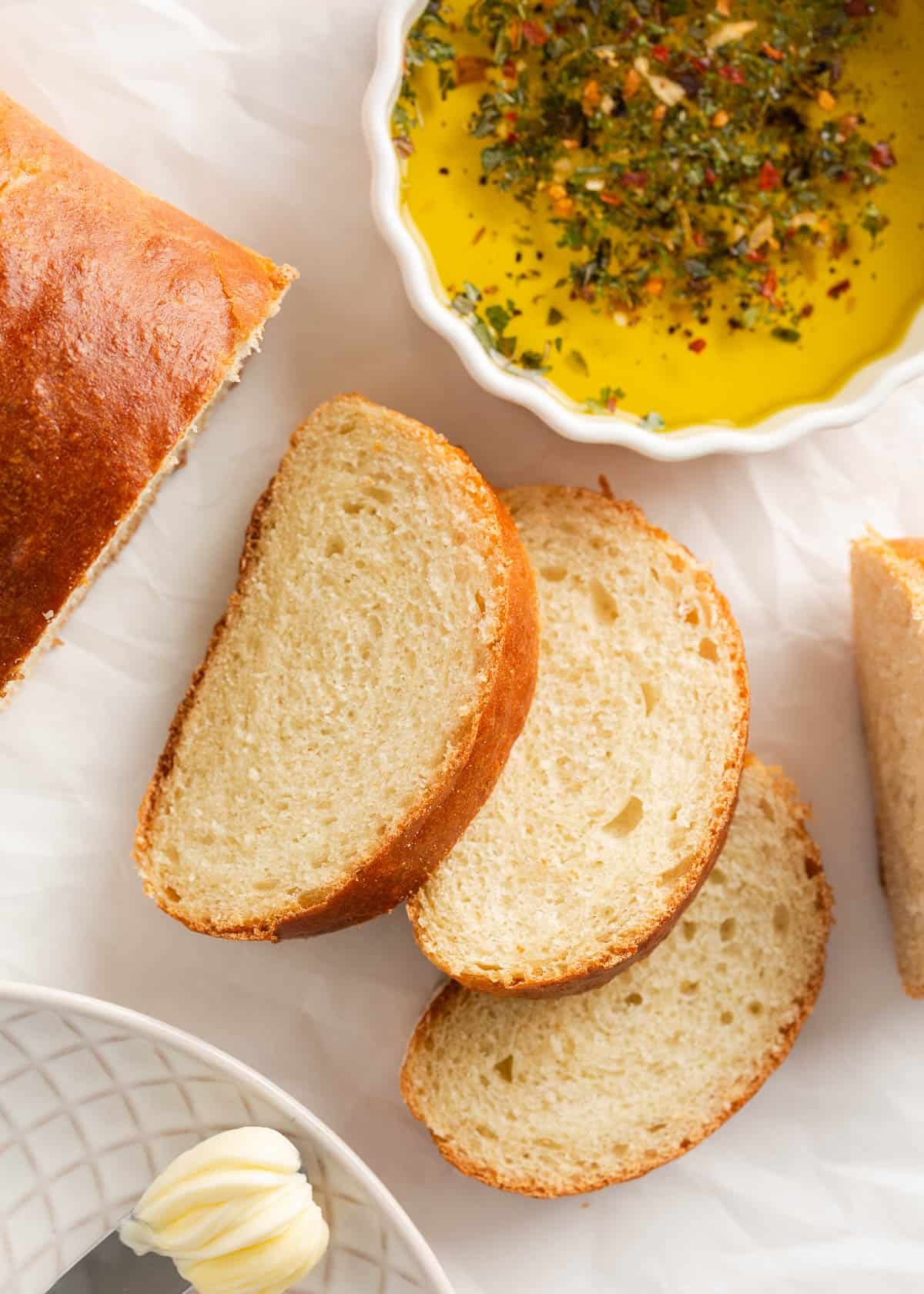 This easy Italian bread recipe is ready in just under 2 hours, including rise time. No bread maker is needed; all the kneading is done in a stand mixer, making it easier than you think! Sliced homemade Italian bread on counter with dipping oil.