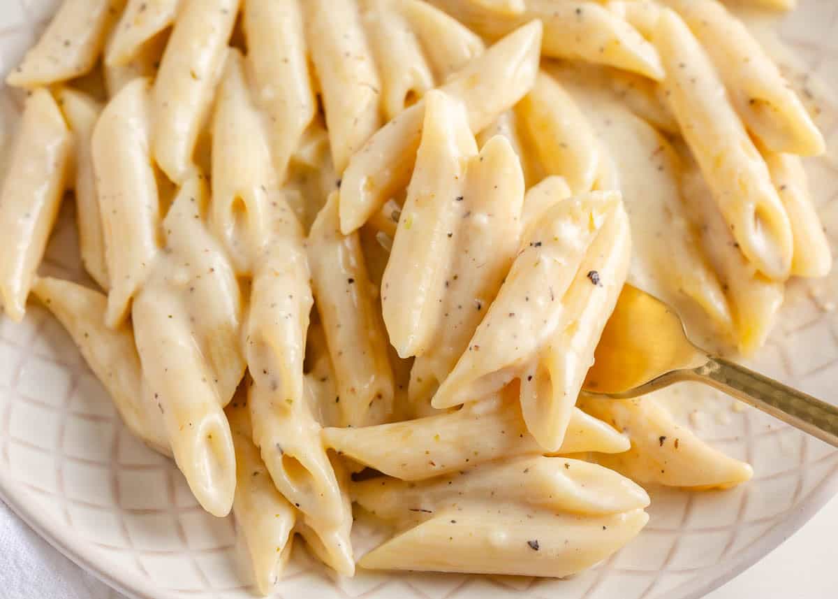 Creamy penne pasta on a white plate.