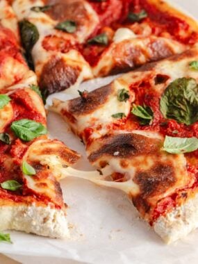 Sourdough discard pizza crust topped with marinara, melted mozzarella, and fresh basil, sliced into pieces.