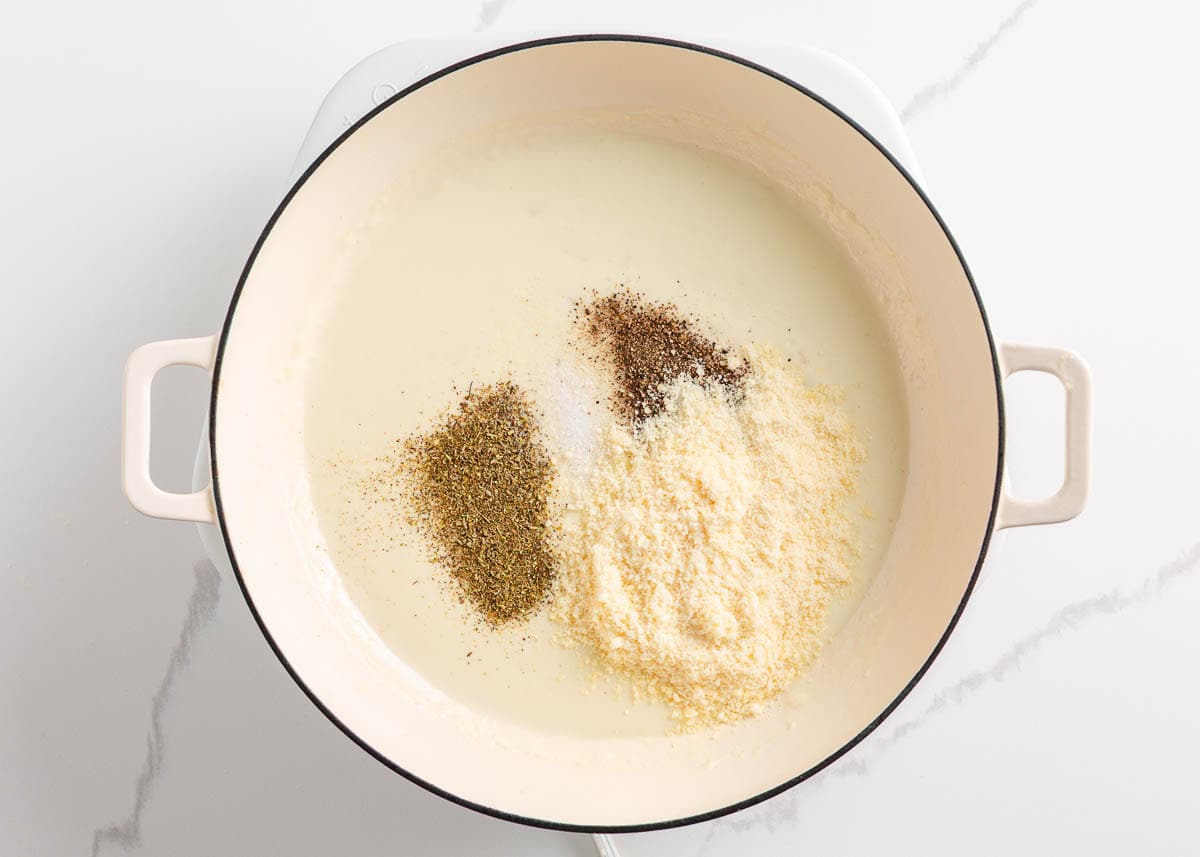 Adding cheese and seasonings into creamy sauce for penne pasta.