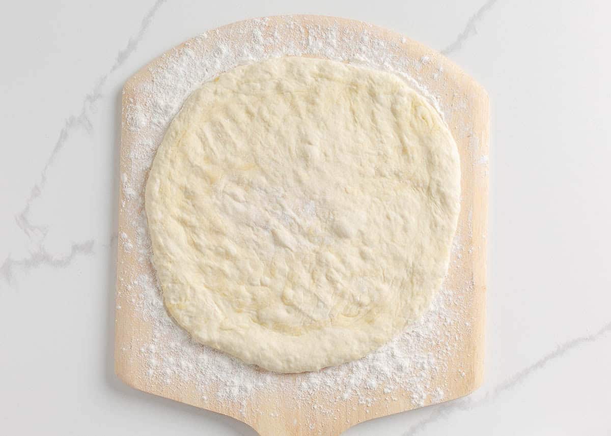 Sourdough pizza dough on baking peel.