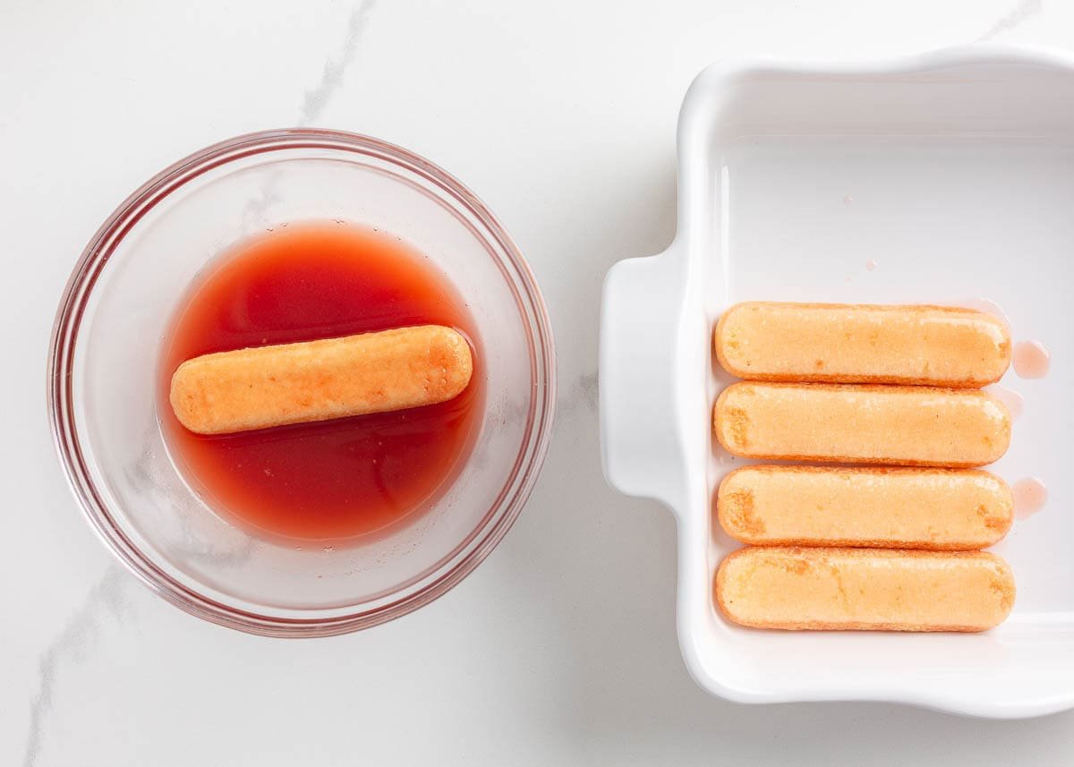 Dipping a ladyfinger cookie into strawberry sauce.