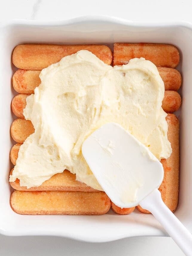 Layering ladyfingers i in a pan with mascarpone mixture.
