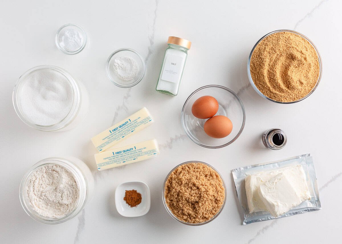 Butter, graham cracker crumbs, sugar, brown sugar, flour, eggs, cream cheese and vanilla on the counter.