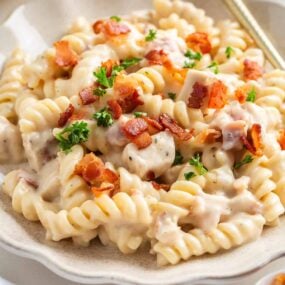 Chicken bacon ranch pasta on a white plate with gold fork.