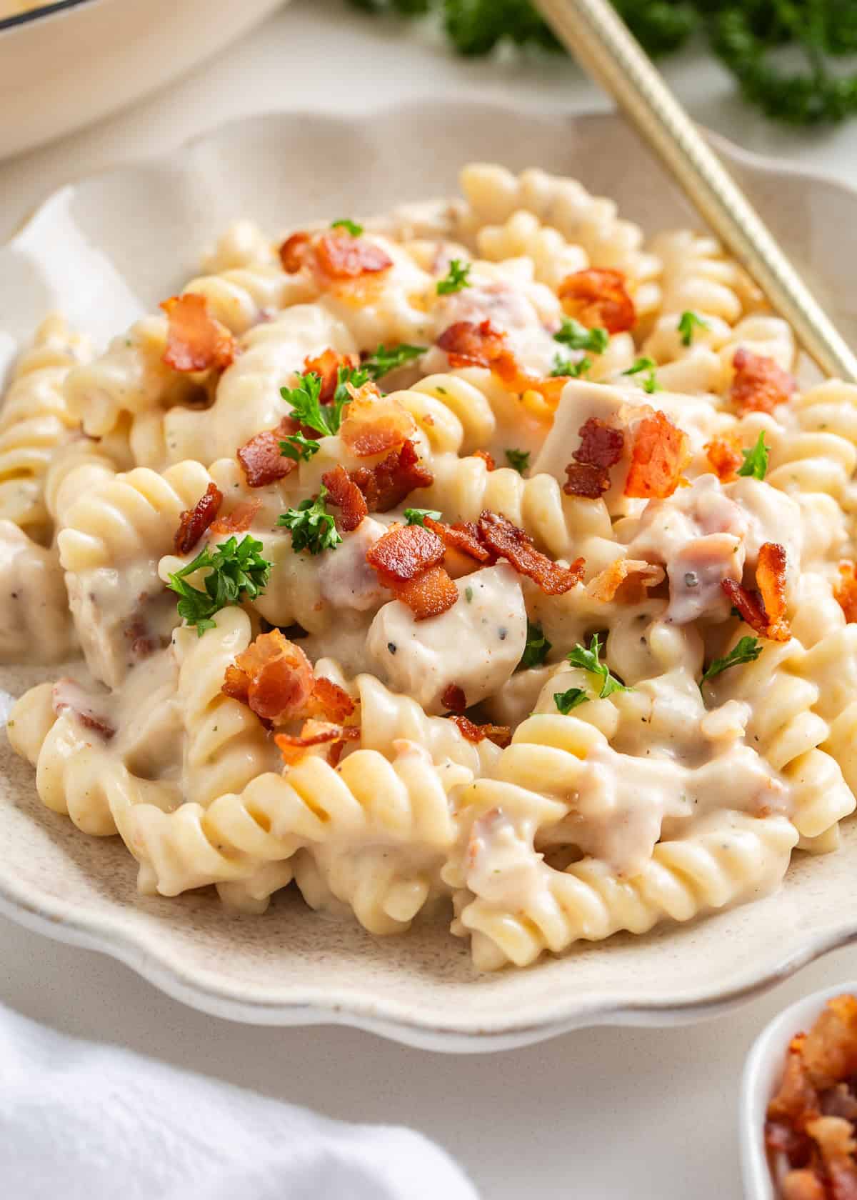 Chicken bacon ranch pasta on a white plate with gold fork.