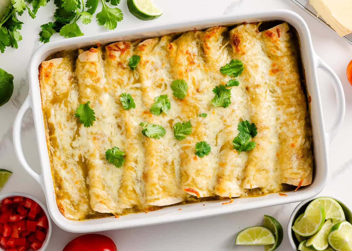 This recipe for cream cheese chicken enchiladas is a simple, creamy, cheesy, and zesty Mexican-inspired dinner idea. Bake until bubbly and serve with your favorite toppings! Cream cheese chicken enchiladas in a baking dish.