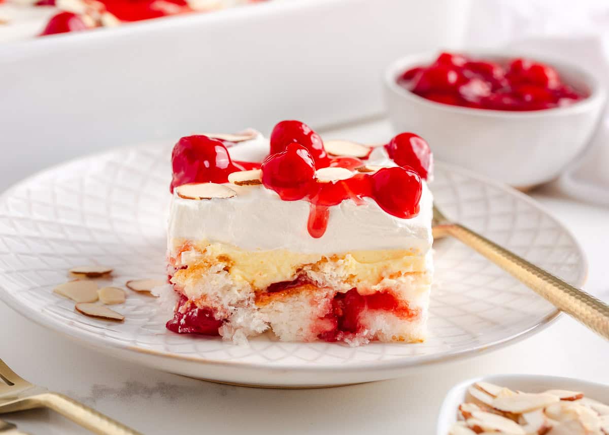 A slice of heaven on earth cake on a white plate with a gold fork.