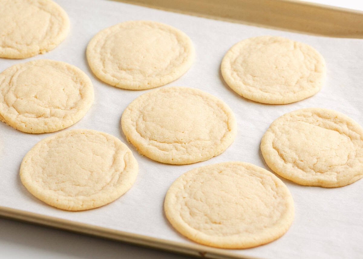 Chewy sugar cookies on parchment lined baking sheet.
