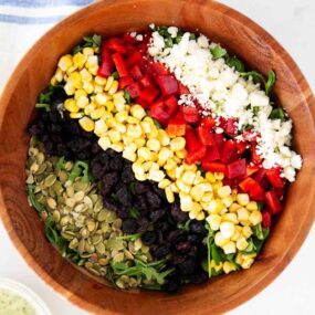 Arugula chopped salad with creamy basil dressing in a large salad bowl.