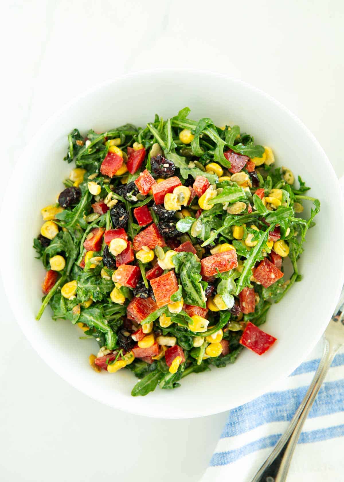 Chopped arugula salad tossed in a white salad bowl.