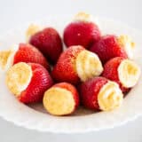 Cheesecake stuffed strawberries on a plate.