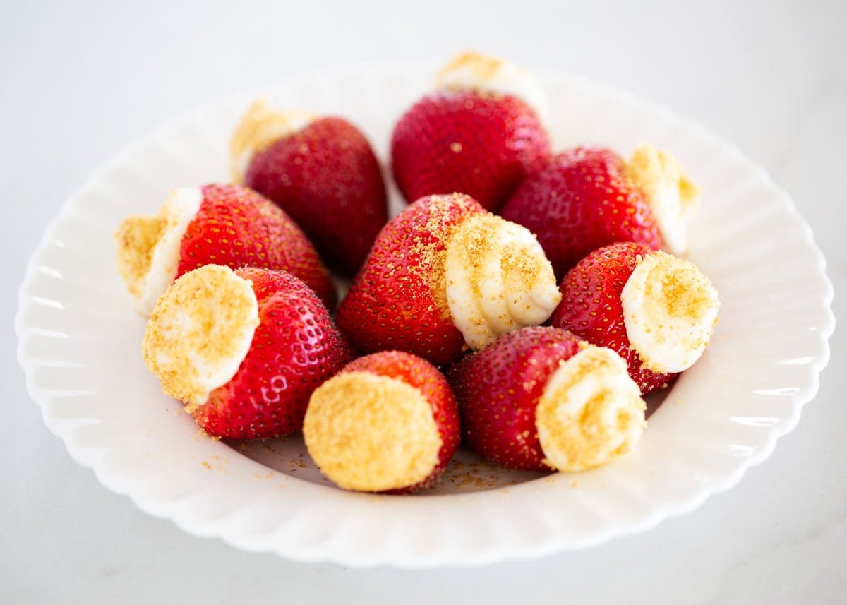 Cheesecake stuffed strawberries on a plate.