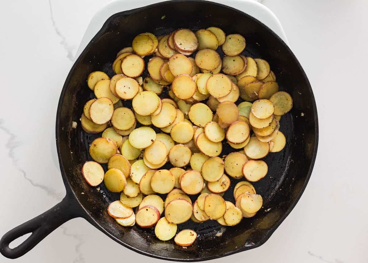 Sliced potatoes pan-fried until golden and tender in a skillet.