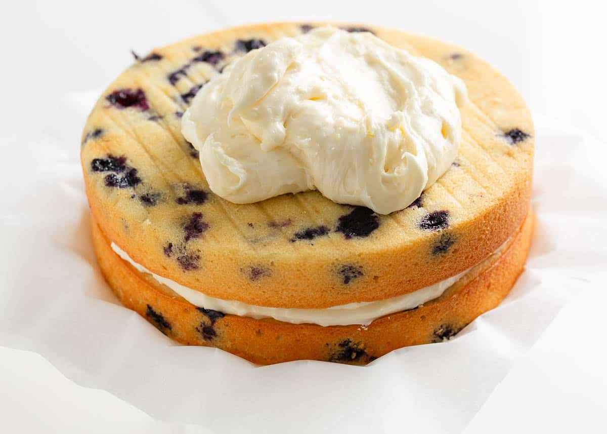 Lemon blueberry layer cake layers stacked with lemon cream cheese frosting between them.