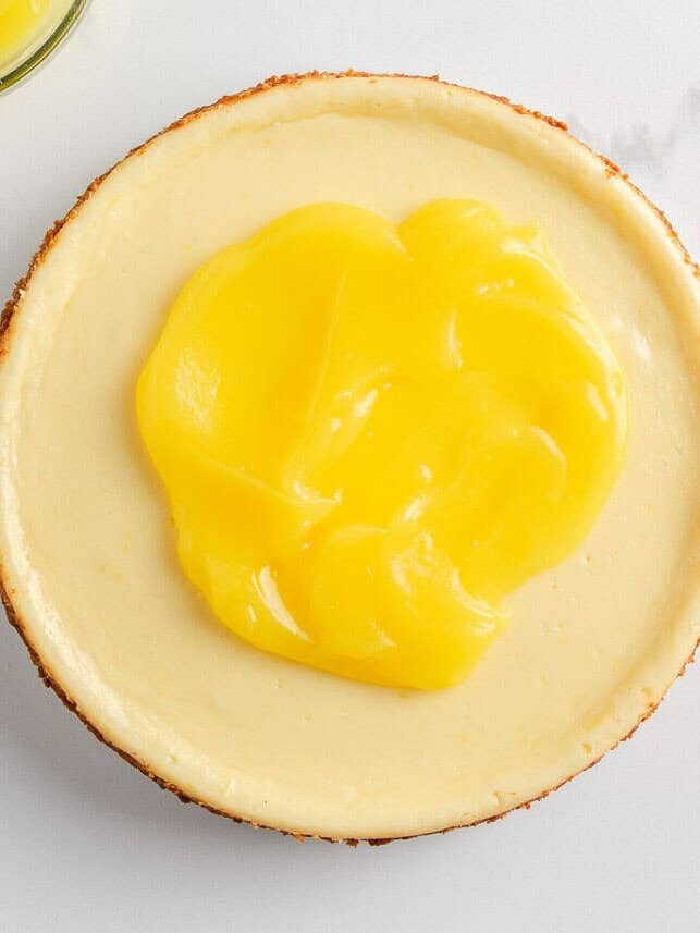 Spreading lemon curd on top of lemon cheesecake.
