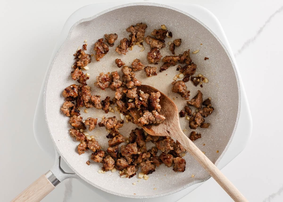 Cooking breakfast sausage in a skillet for Easy Potatoes O’Brien breakfast casserole.