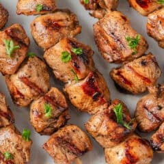 A plate of chicken skewers garnished with parsley.