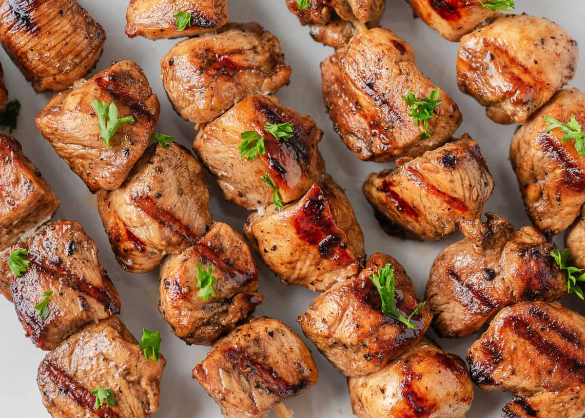 A plate of chicken skewers garnished with parsley.