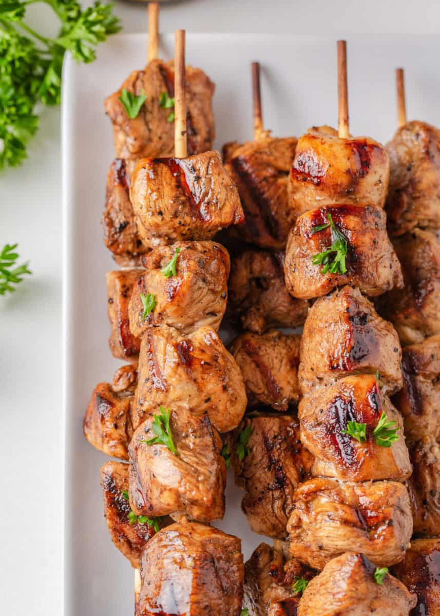 Chicken skewers on a white plate.