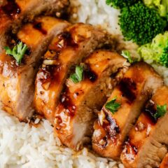 Sliced grilled honey garlic chicken breast plated with rice and broccoli.