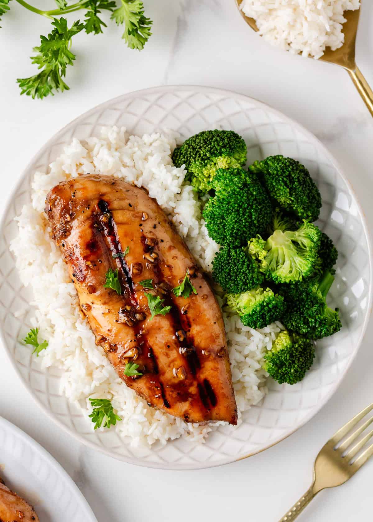 Honey garlic chicken breast on a plate with rice and broccoli.