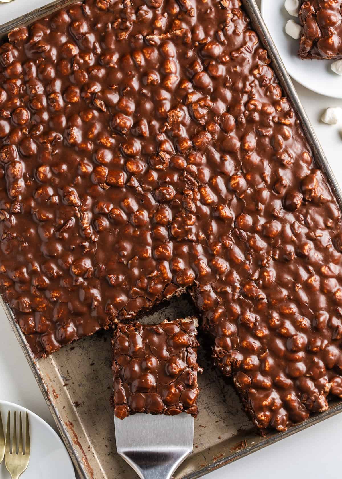 Showing an overhead shot of Mississippi mud cake in a sheet pan with serving spatula.