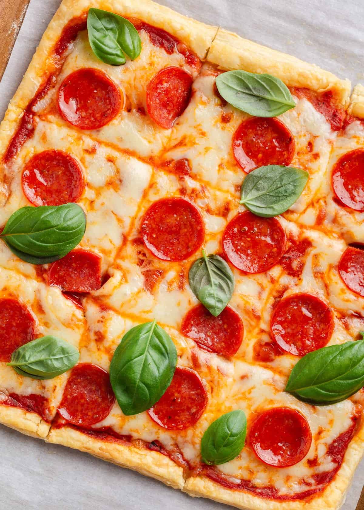 Puff pastry pizza with pepperoni and basil.