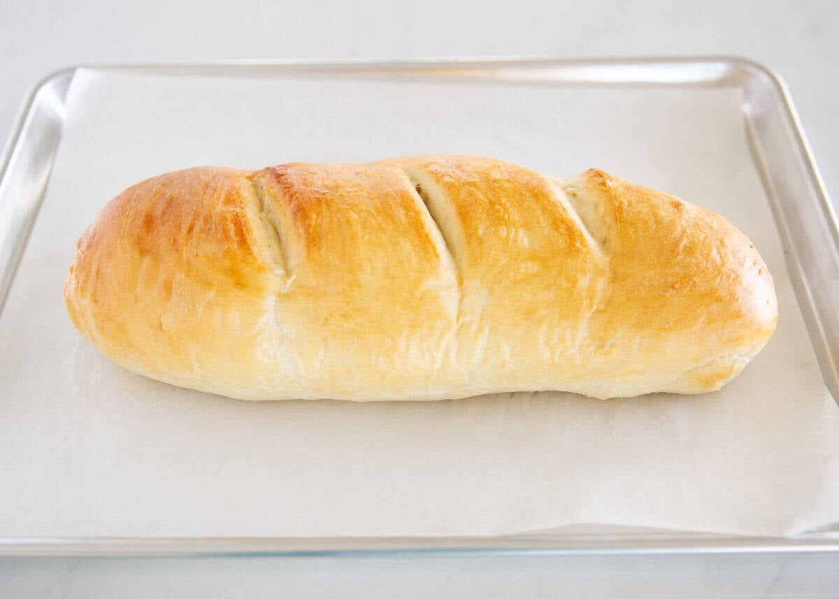 Homemade Italian bread loaf baked until golden brown on a parchment lined baking sheet.