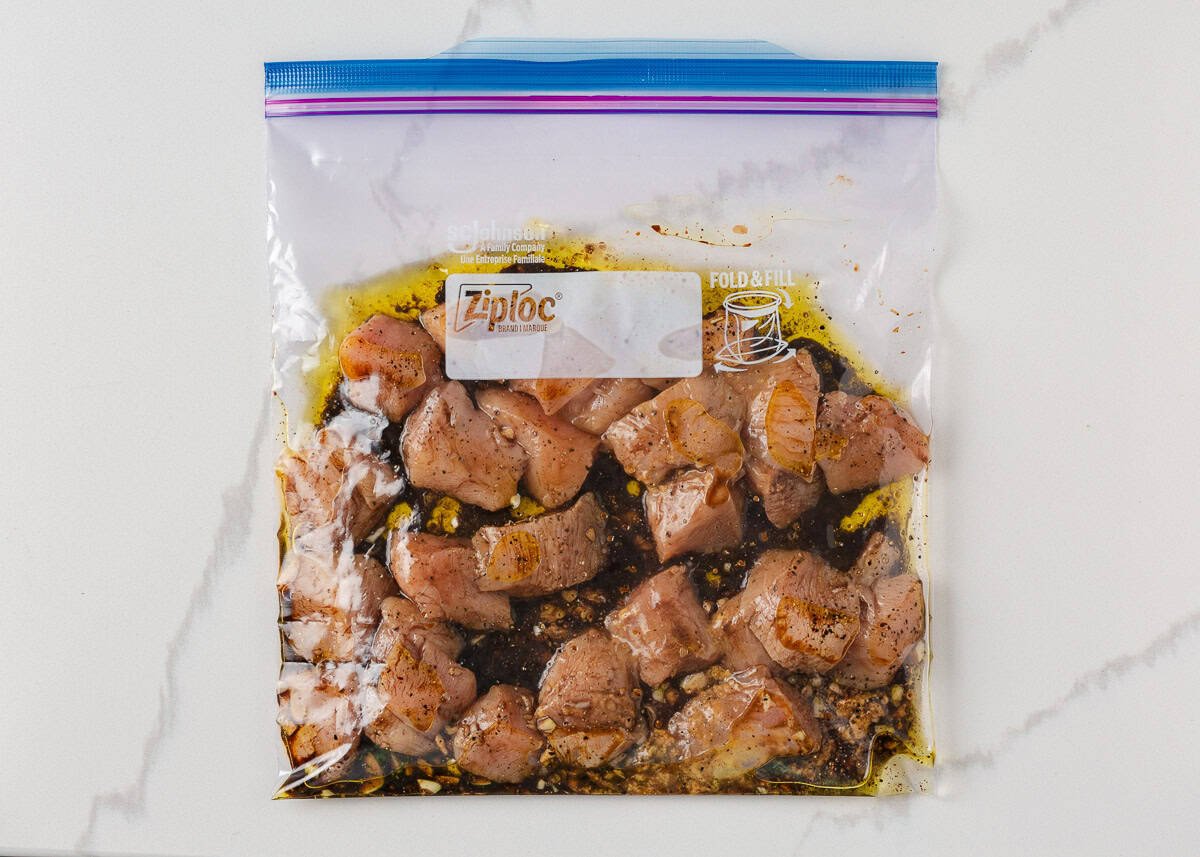 Cubed chicken breast in a ziploc bag with marinade. 