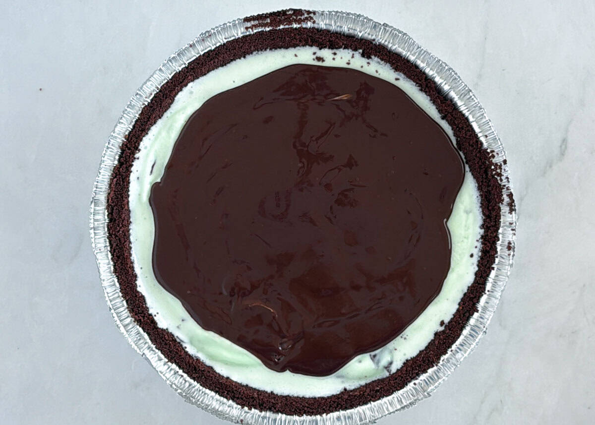Showing adding chocolate ganache on top of min ice cream.