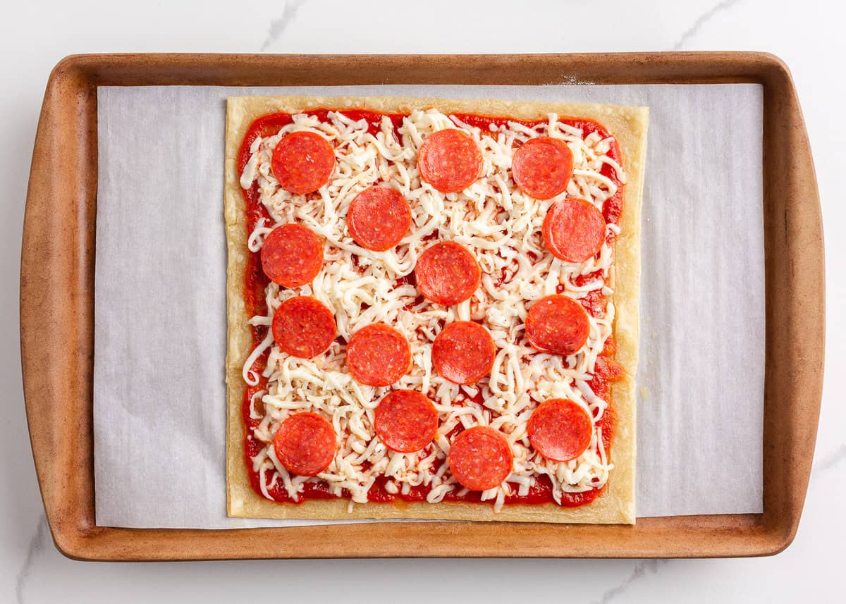 Unbaked puff pastry pizza on baking sheet.