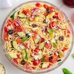 Cold spaghetti salad in a bowl with fresh veggies and tender noodles coated in zesty Italian dressing.