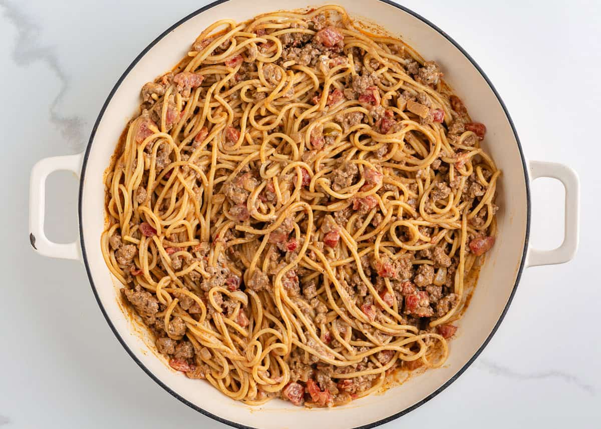 Cooked spaghetti stirred into the creamy taco beef mixture in a large skillet.