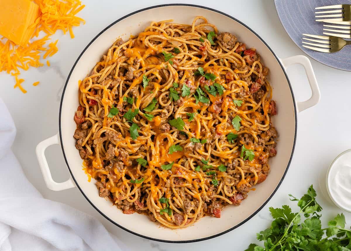 Taco spaghetti topped with shredded cheese and fresh cilantro, ready to serve.