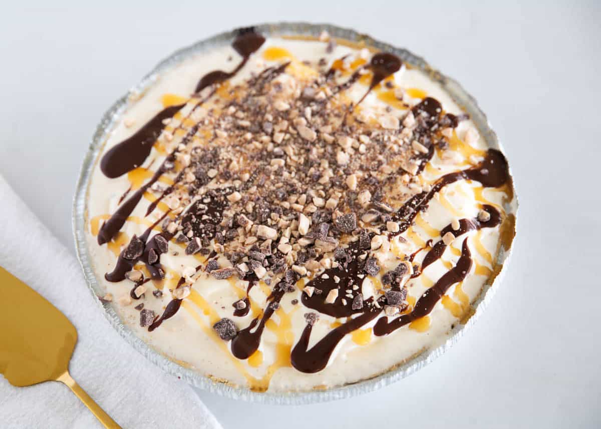 This easy ice cream pie layers vanilla ice cream in a graham cracker crust with hot fudge, caramel, and toffee bits. A no-bake summer dessert favorite with only 5 ingredients! Frozen ice cream pie topped with caramel sauce, hot fudge, and toffee bits.